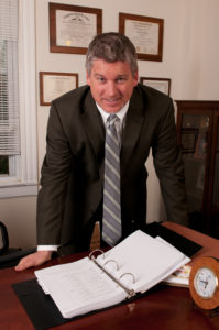 Paul J. Dickman standing at his desk at the Dickman Law Office