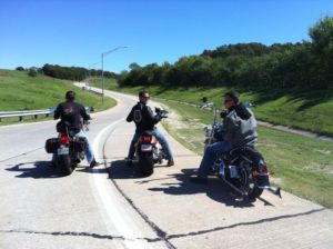 Three people riding motorcycles on a quiet road