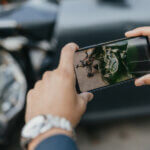 Man taking picture of car with smart phone after accident