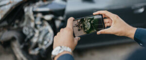 Man taking picture of car with smart phone after accident