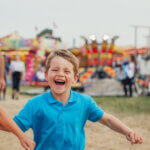 Kids running at a festival while parents walk behind
