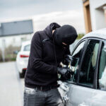 Car thief trying to break into a car with a screwdriver